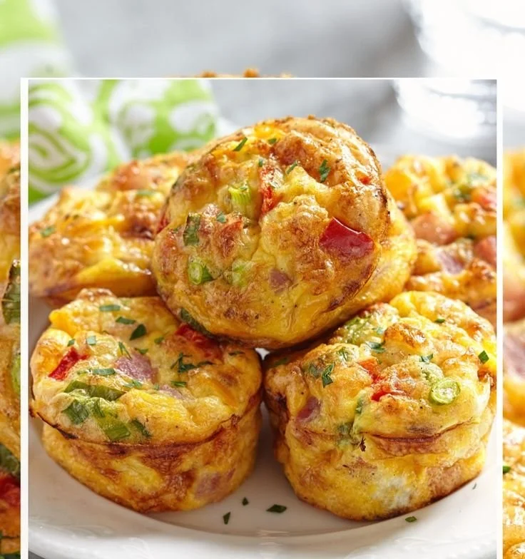 Healthy egg muffins baked in a muffin tin, topped with vegetables and herbs.